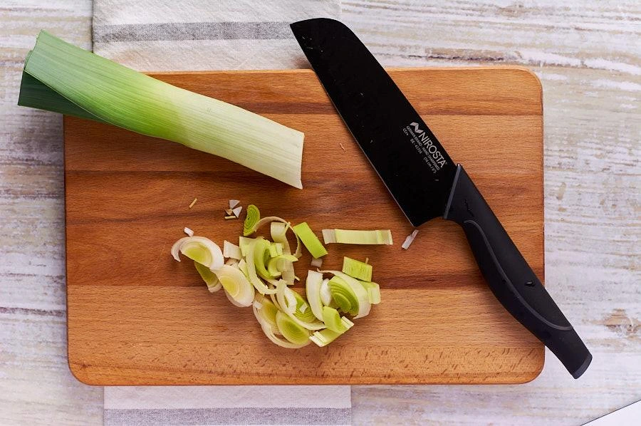 Frischen Lauch auf dem Schneidebrett in feine Ringe schneiden – Schritt für Schritt für eine cremige Lauchcremesuppe.