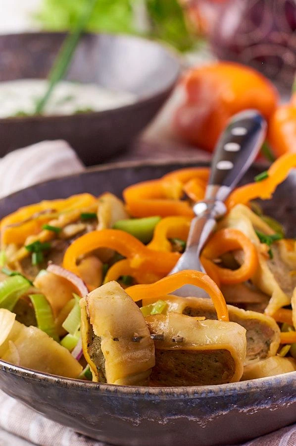 Nahaufnahme von goldbraun gebratenen Maultaschen mit Paprika und Zwiebeln