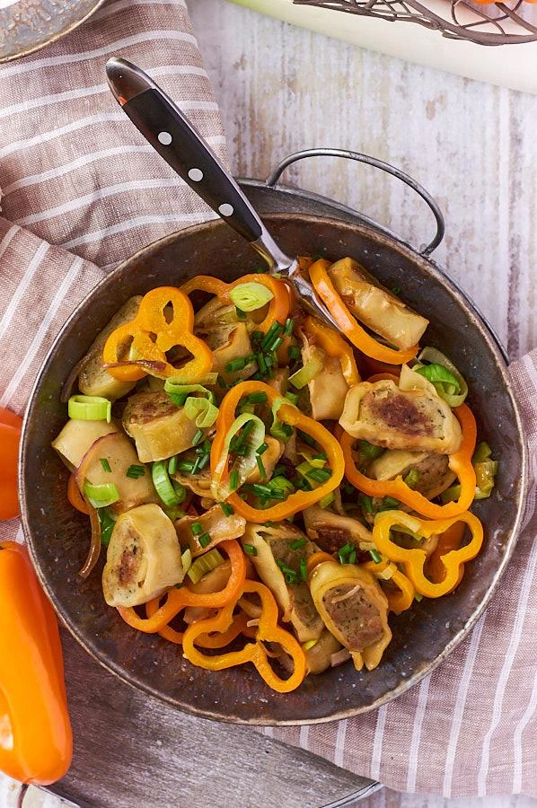 Maultaschen-Pfanne mit Gemüse in einer gusseisernen Pfanne auf Holztisch serviert