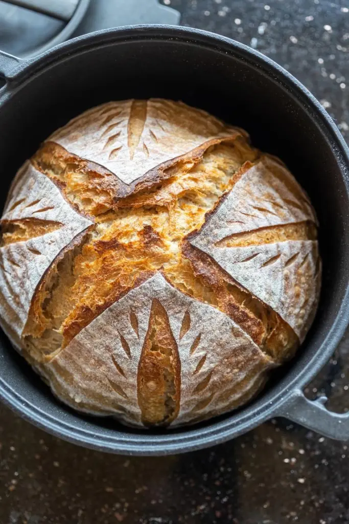 Frisch gebackenes Sauerteigbrot mit Scoring-Muster im Gusseisentopf