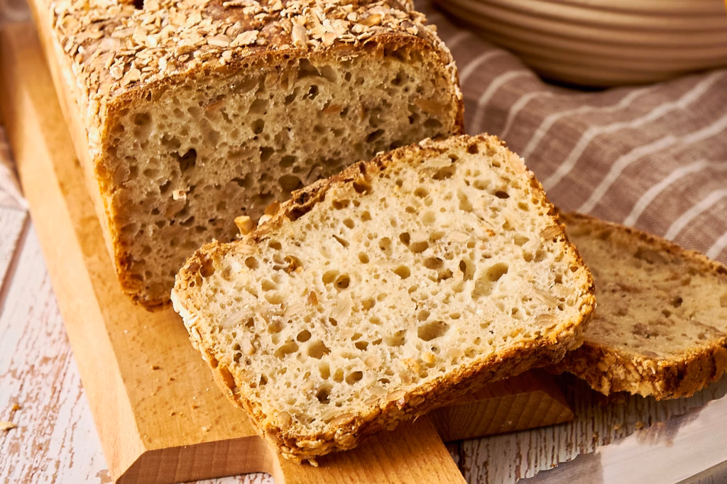 Nahaufnahme einer Dinkelbrotscheibe mit feinporiger, saftiger Krume und Sonnenblumenkernen