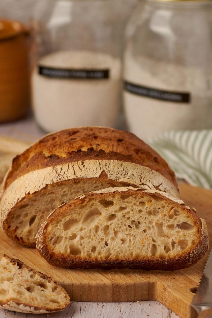 Angeschnittenes Emmer-Dinkel-Karotten-Brot mit Scheiben auf rustikalem Holzbrett