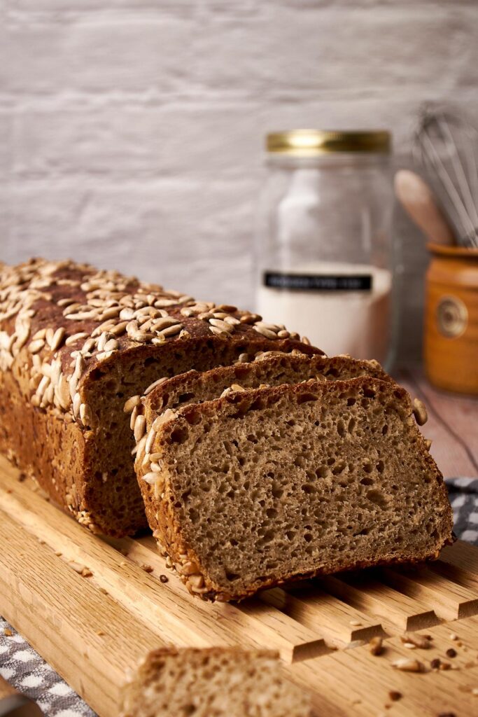Einfaches Roggenbrot ohne Kneten mit Sonnenblumenkernen und saftiger Krume auf Holzbrett