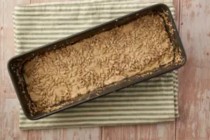 Sonnenblumenkerne auf Roggenmischbrot-Teig in Kastenform verteilen