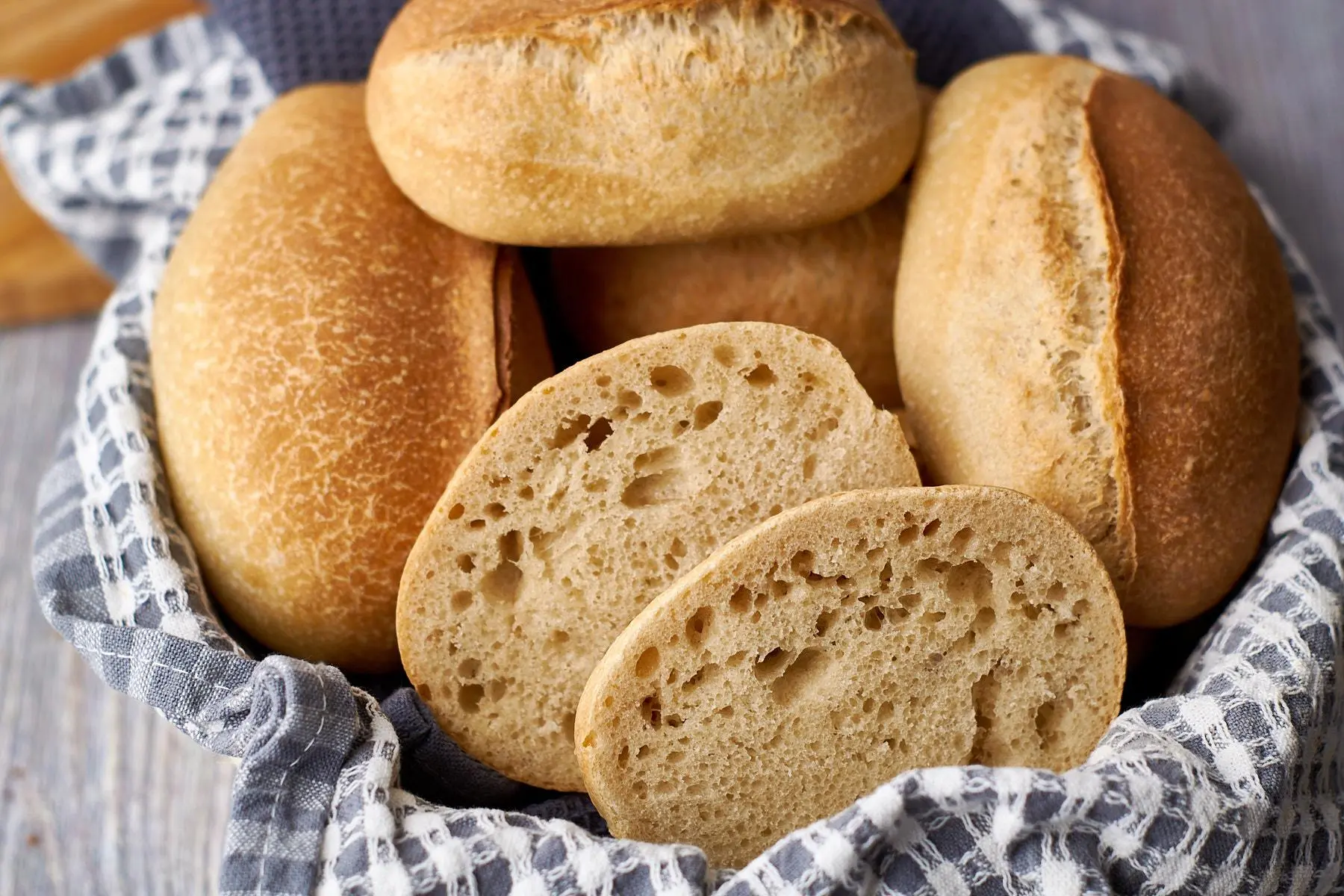 Gestapelte Sonntagsbrötchen mit goldbrauner Kruste, aufgeschnittene Hälften zeigen perfekte luftige Porung