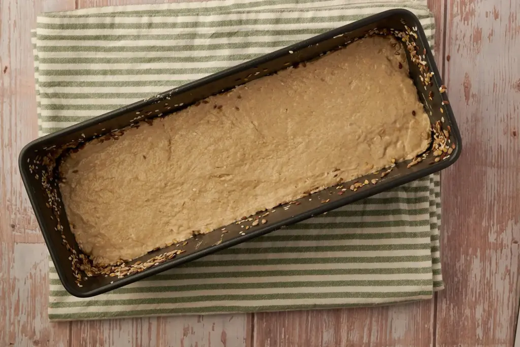 Roggenmischbrot-Teig mit nassen Händen in Kastenform glatt streichen