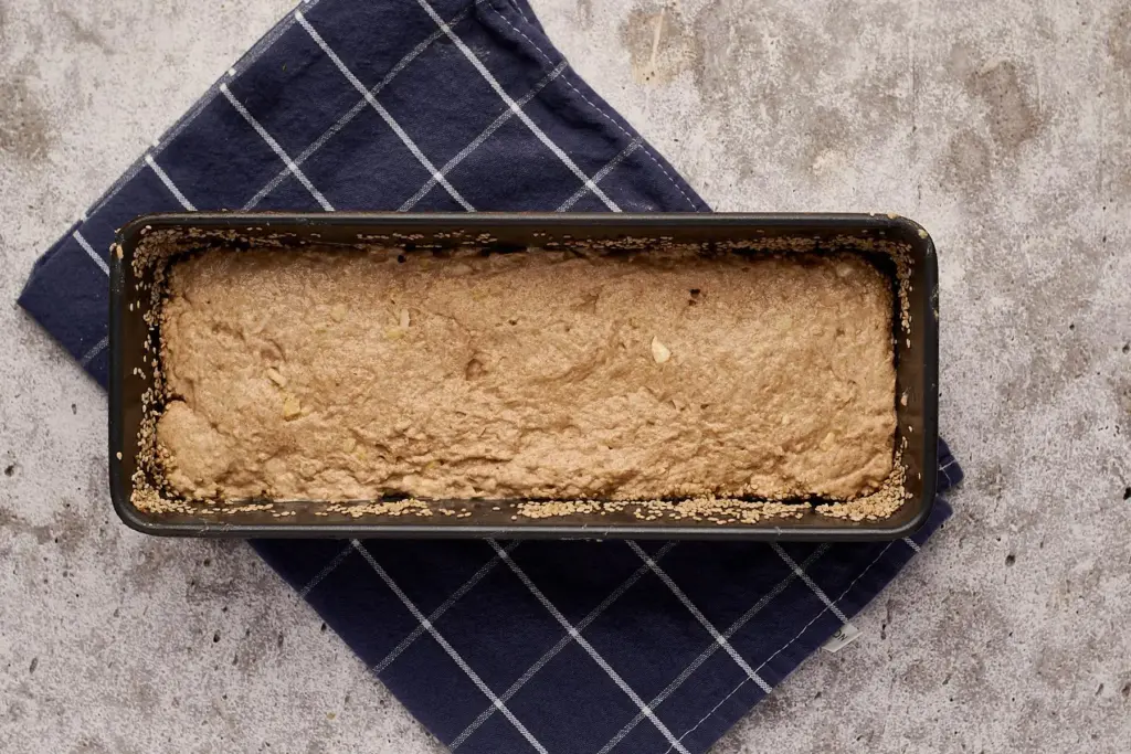 Teigling für saftiges Dinkelvollkornbrot mit Sauerteig in Kastenform vor dem Bestreuen