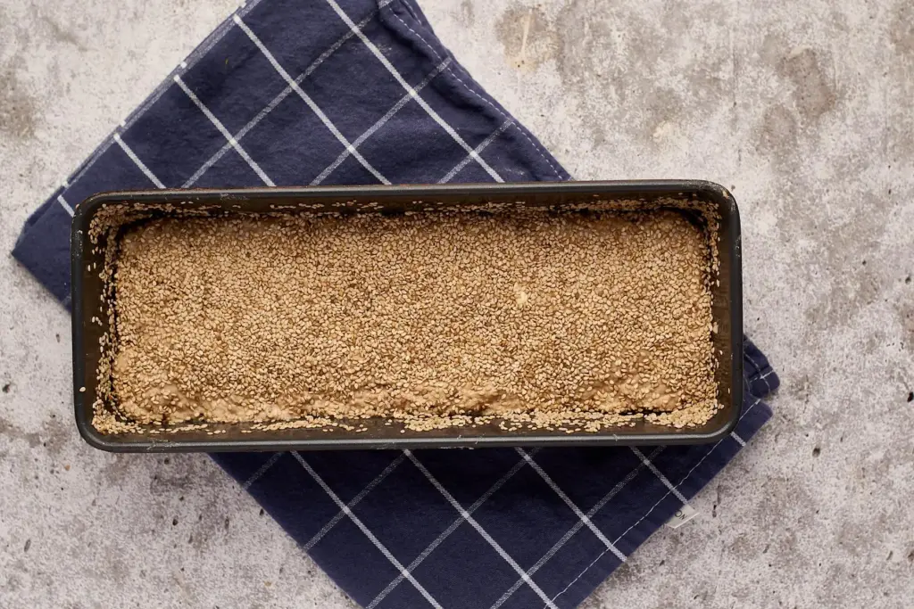 Saftiges Dinkelvollkornbrot mit Sauerteig in Kastenform mit Sesam vor dem Backen