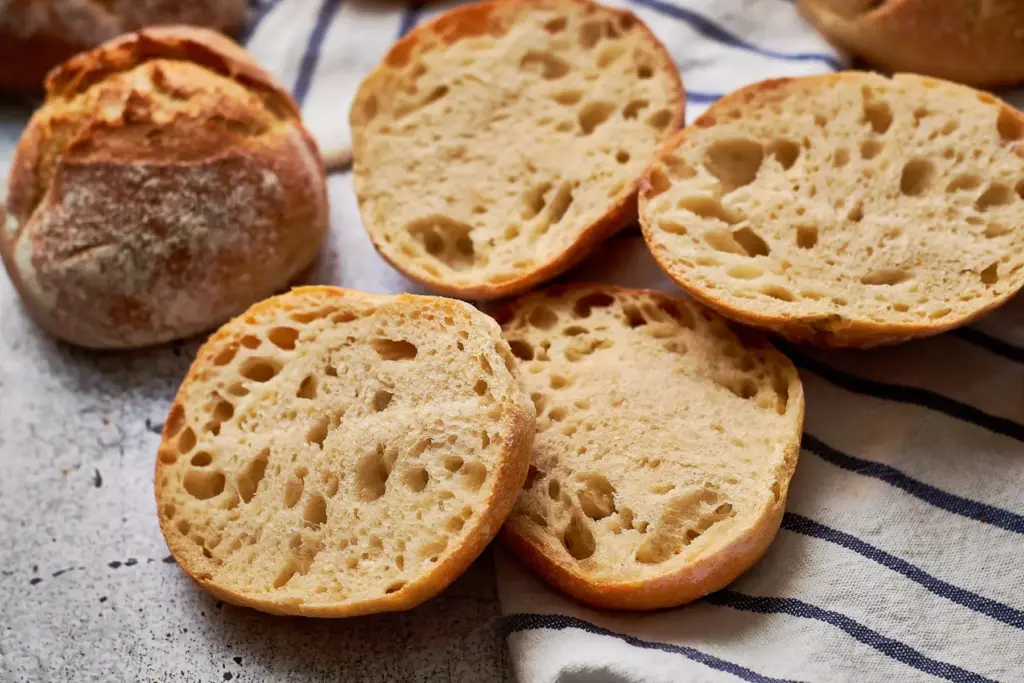Aufgeschnittene Einkorn-Dinkel-Brötchen auf Küchentuch, luftige Krume mit unregelmäßiger Porung