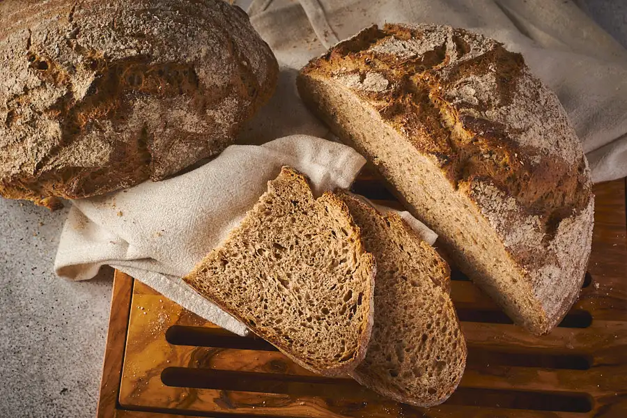 Angeschnittener Limpurger Schrotlaib mit zwei Scheiben, saftige Krume mit feiner Porung sichtbar