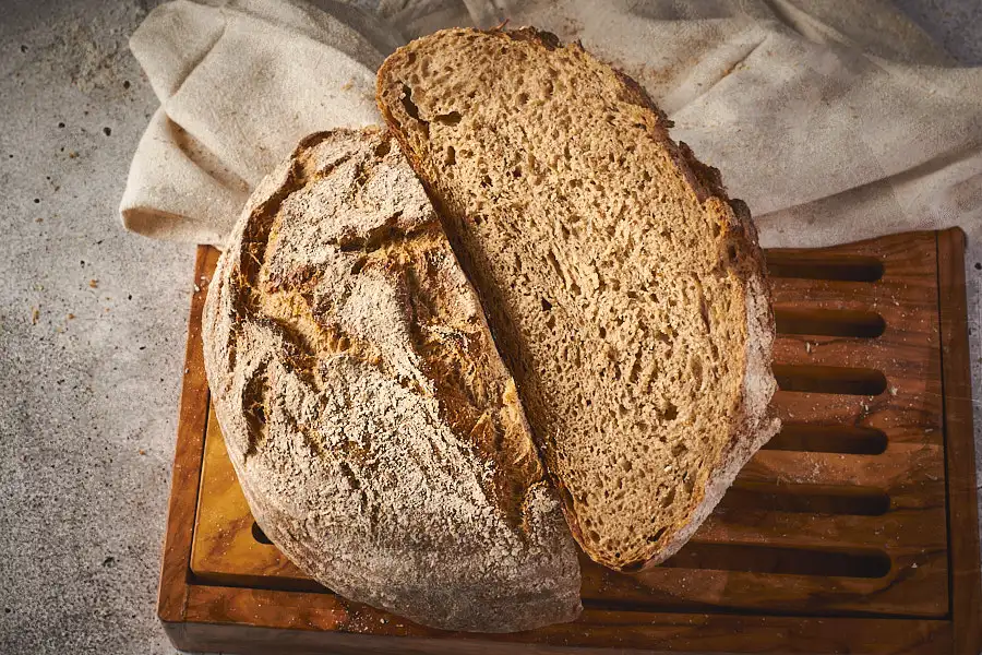 Aufgeschnittener Limpurger Schrotlaib auf Schneidebrett, Krume und Kruste von oben fotografiert