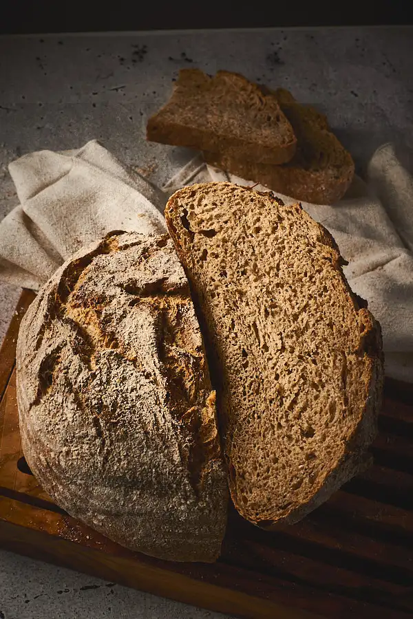 Limpurger Schrotlaib halbiert mit Brotscheiben im Hintergrund, rustikales Brot selber backen