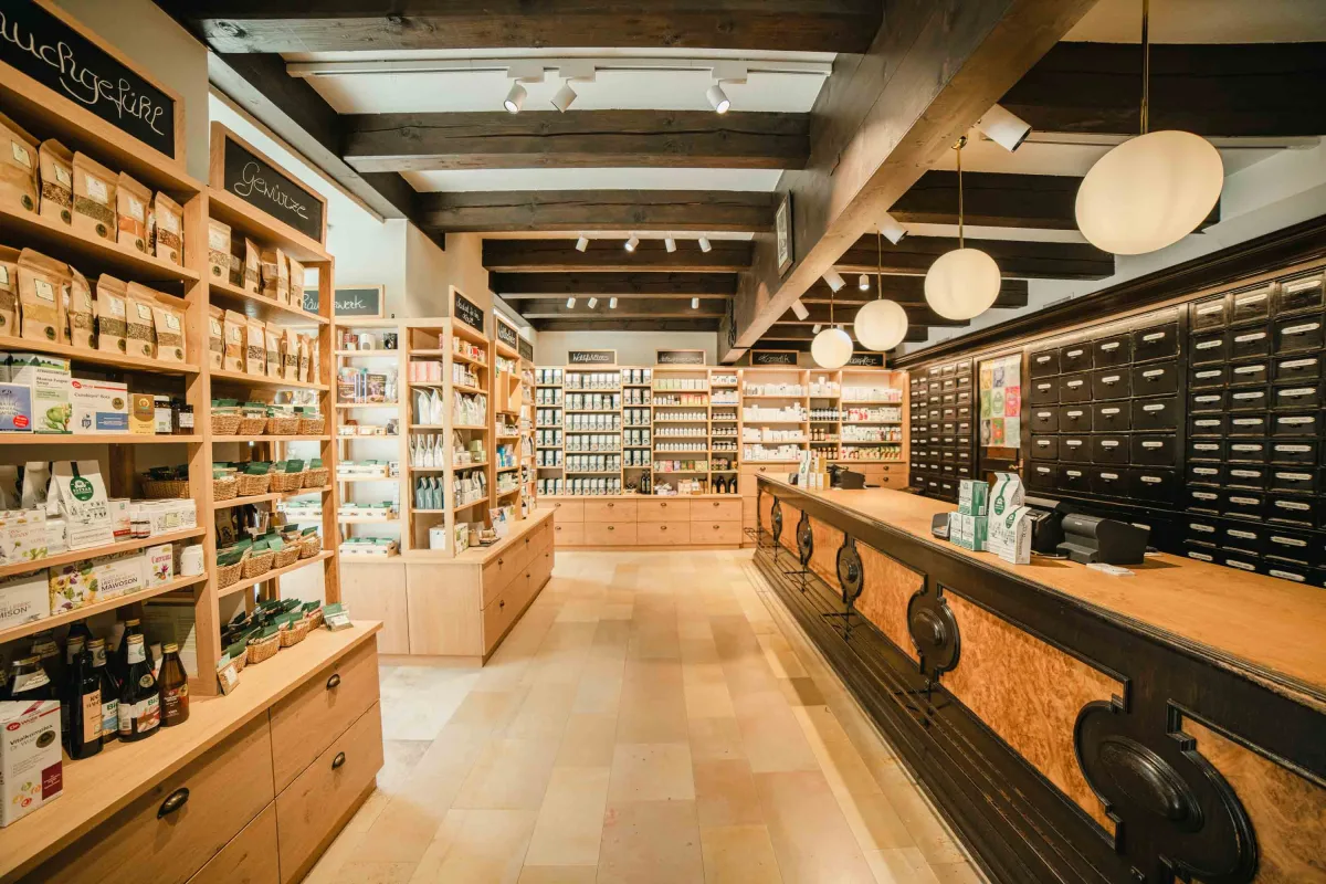 Innenraum des Kräuterhaus Kottas in Wien mit Holzregalen voller loser Gewürze und Kräuter und dunklen Apothekerschubladen